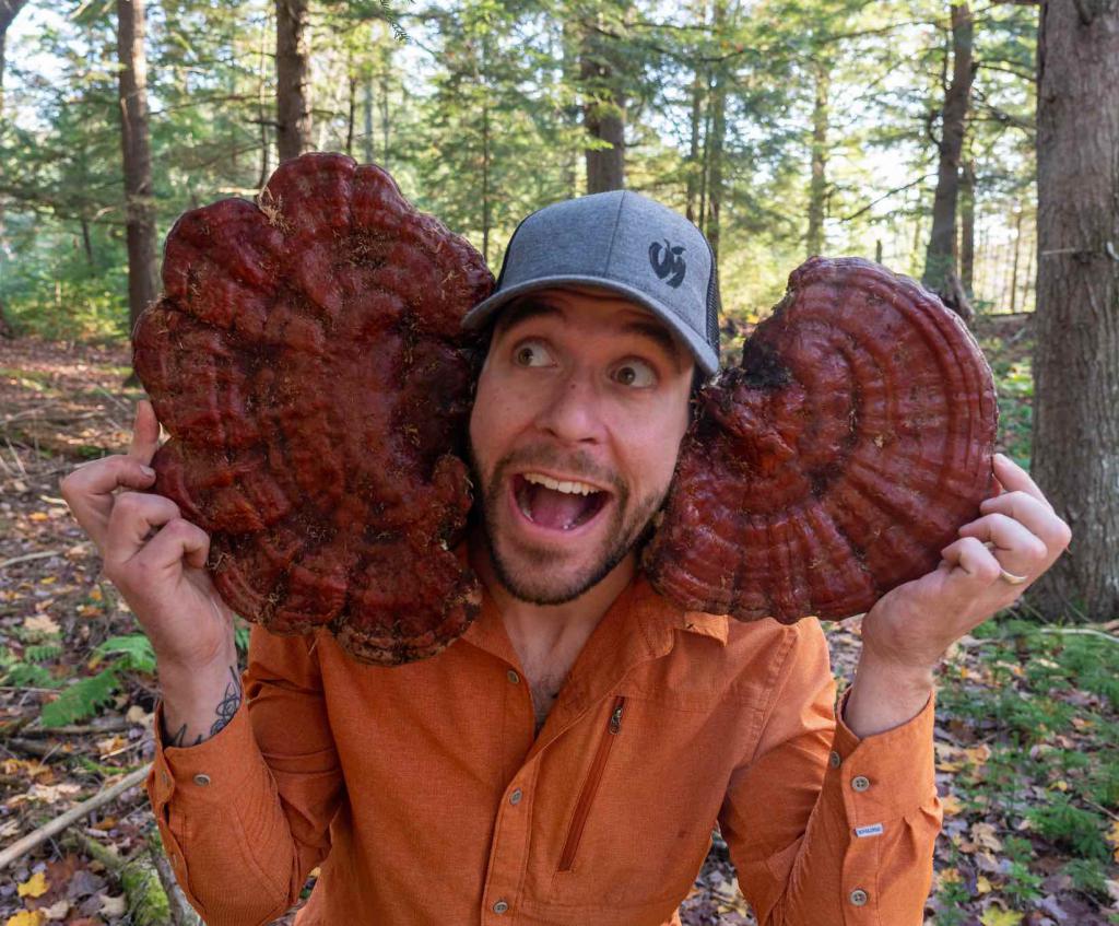 Nathan Miller poses with two giant reishi mushrooms as ears.