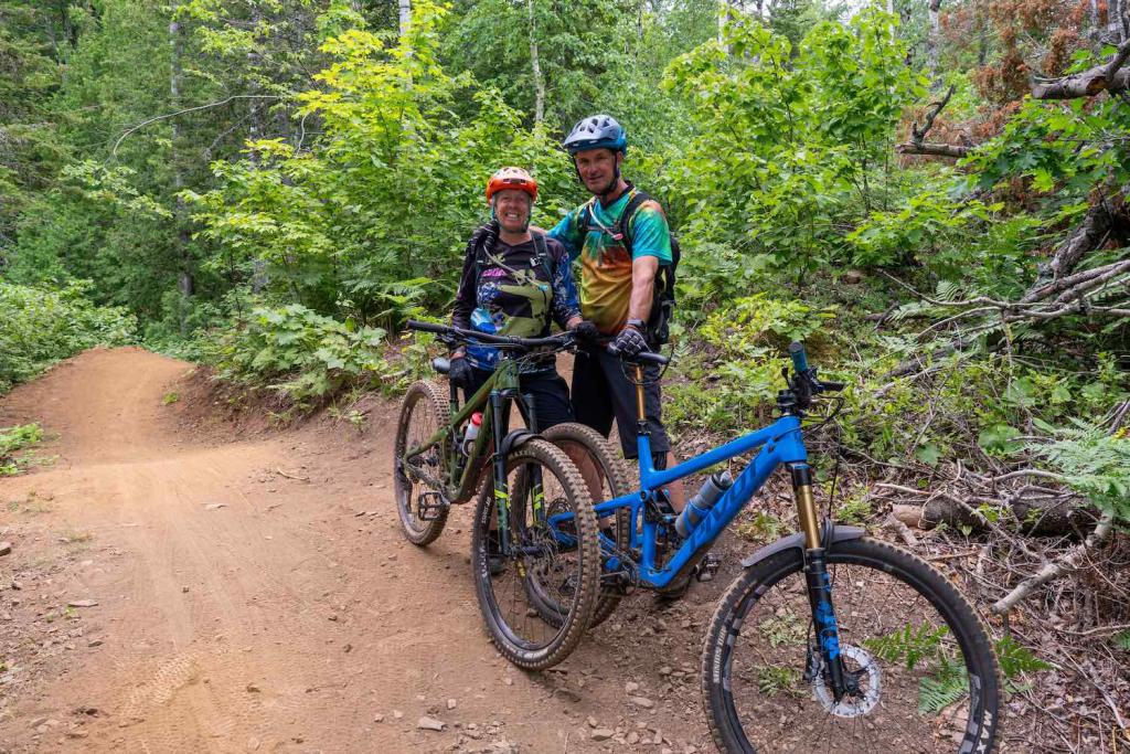 Two riders stand by their mountain bikes