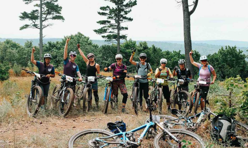 A group of mountain bikers celebrates at a view point